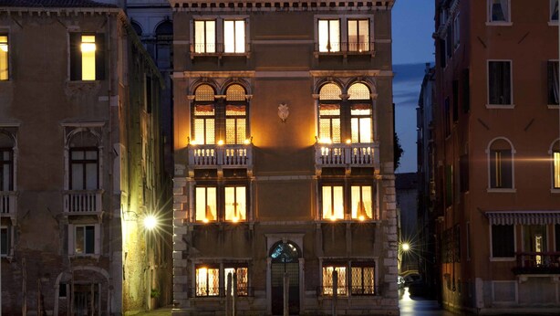 A historic building with multiple balconies and illuminated windows, situated by a canal. - Palazzetto Pisani (Venice)