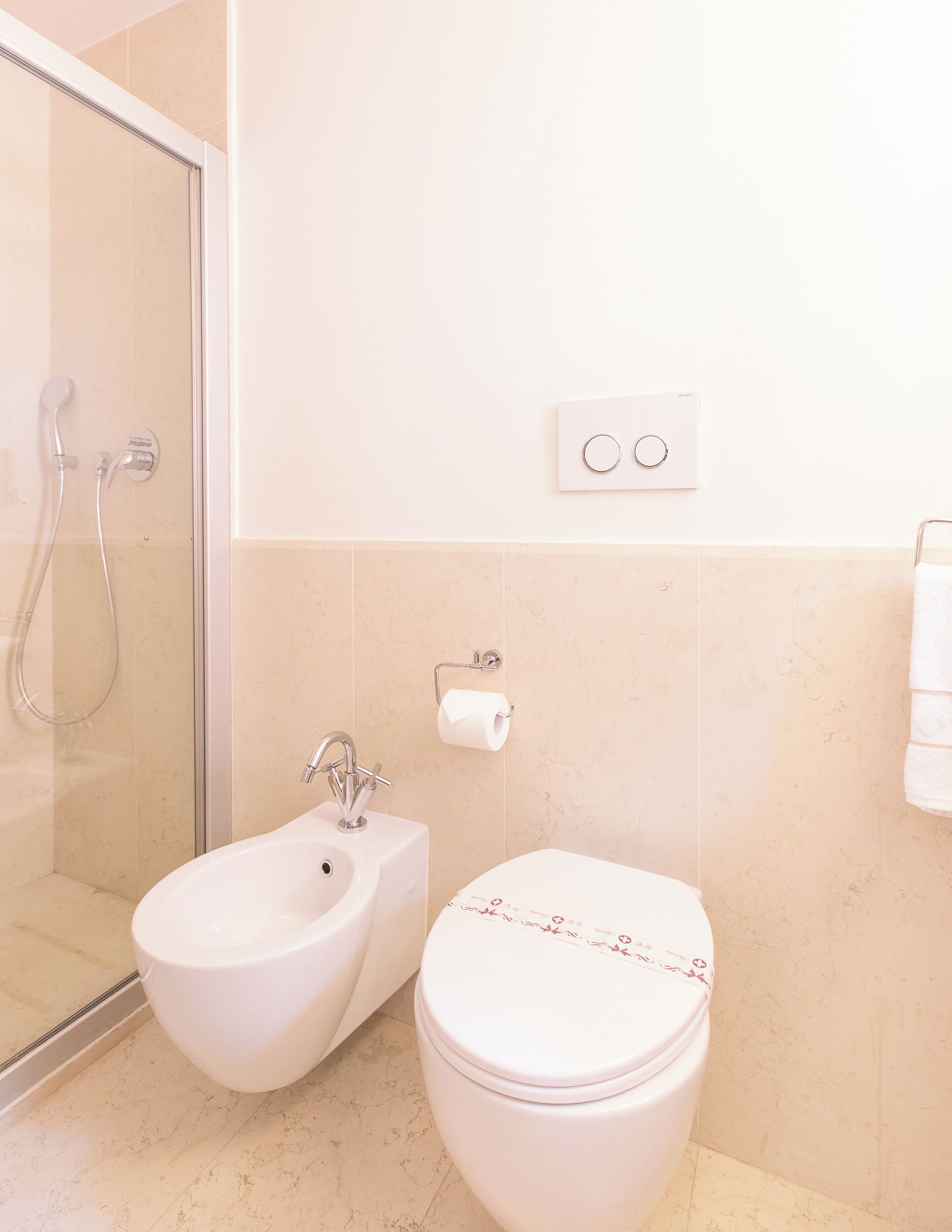 Une salle de bain équipée d’une douche, d’un bidet, de toilettes et d’un porte-serviettes.