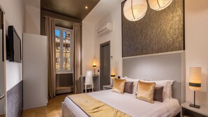 Ein modernes Hotelzimmer mit einem großen Bett, Nachttischlampen, einem Flachbildfernseher und Blick auf die Stadt durch das Fenster.