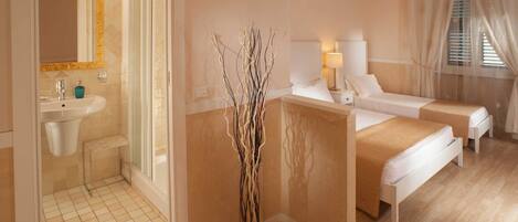 A hotel room with a bathroom, two beds, a bedside table, a lamp, and a decorative vase.