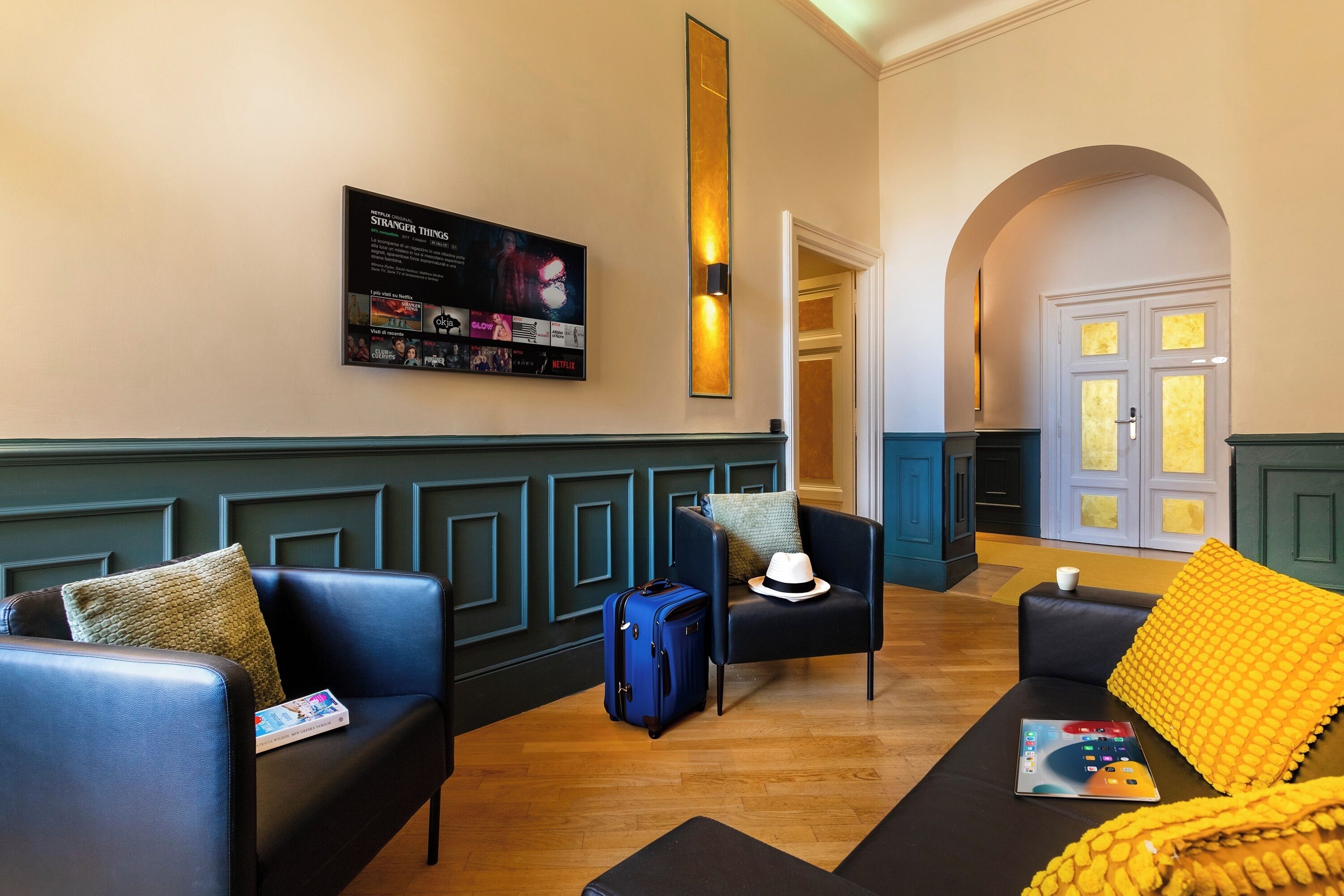 A lobby with a seating area, a wall-mounted TV, and a door leading to another room.