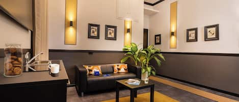 A modern lobby with a sofa, coffee table, and decorative wall sconces.