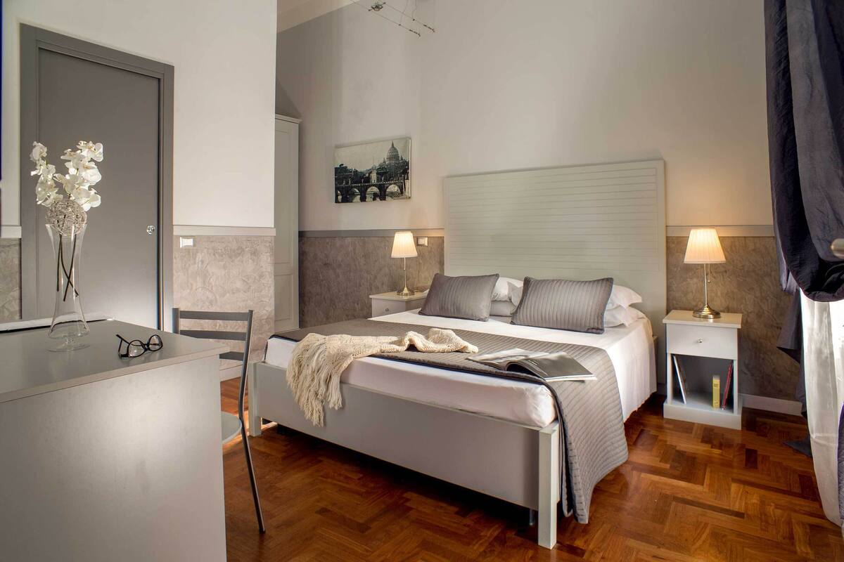 A modern bedroom with a bed, bedside tables, a desk, and a chair.