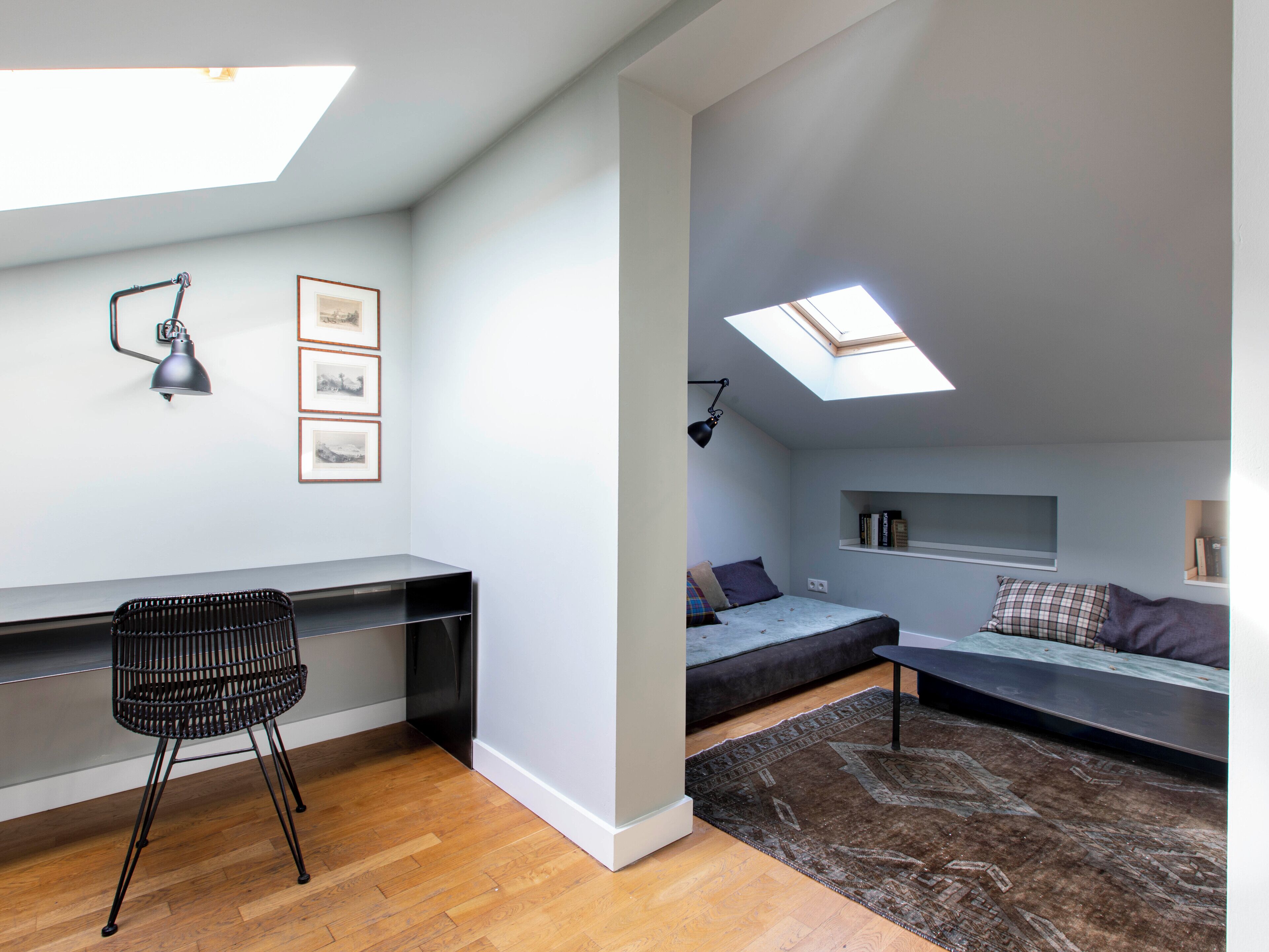 Een moderne loft slaapkamer met dakramen, een bureau, een bed en een zithoek.
