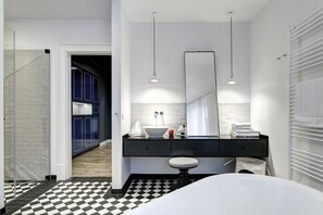 Ein modernes Badezimmer mit einem schwarz-weißen Schachfußboden, einer weißen Badewanne, einem großen Spiegel und einer schwarzen Waschtischvariante mit Waschbecken.