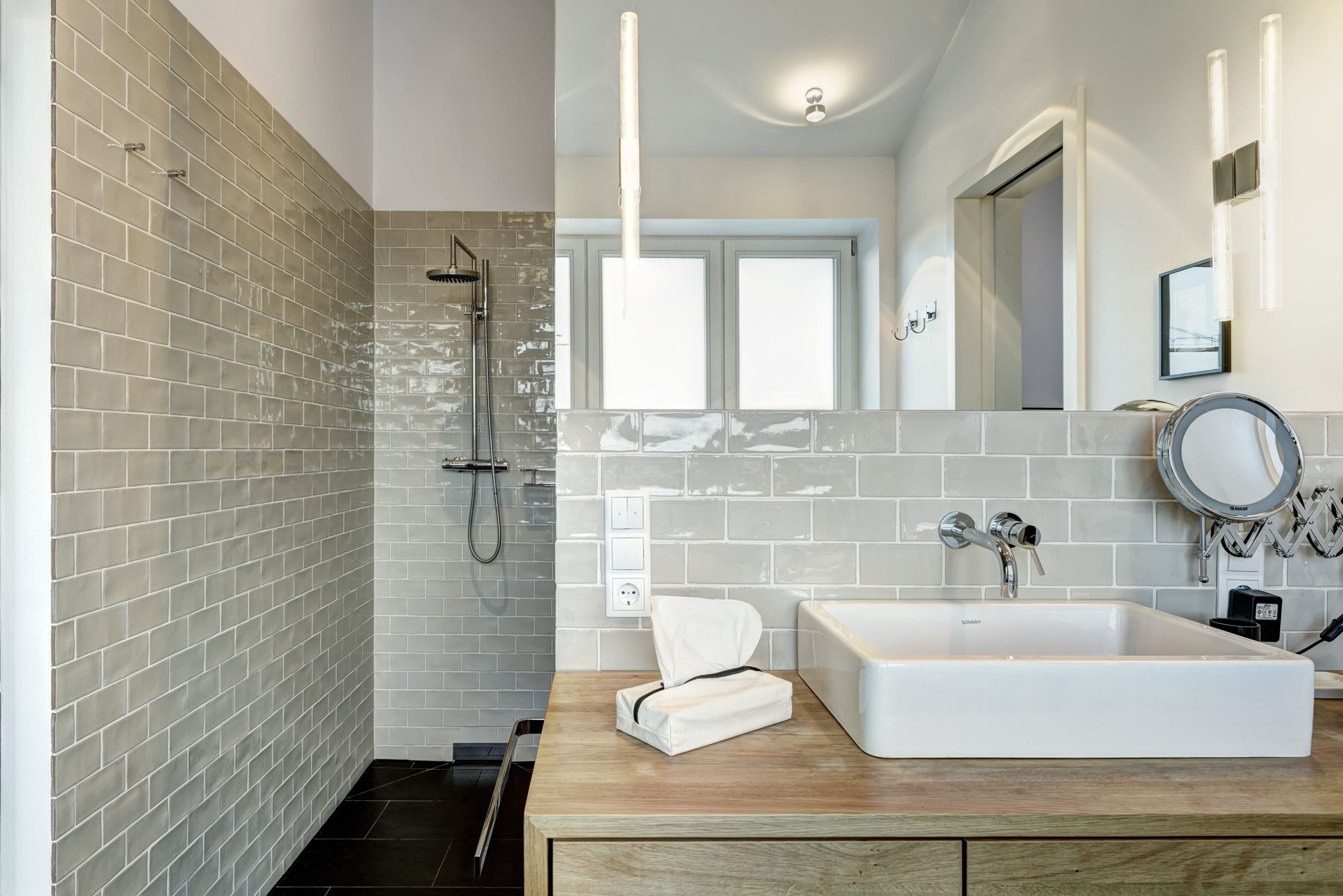 Un baño moderno con ducha, lavamanos y espejo.