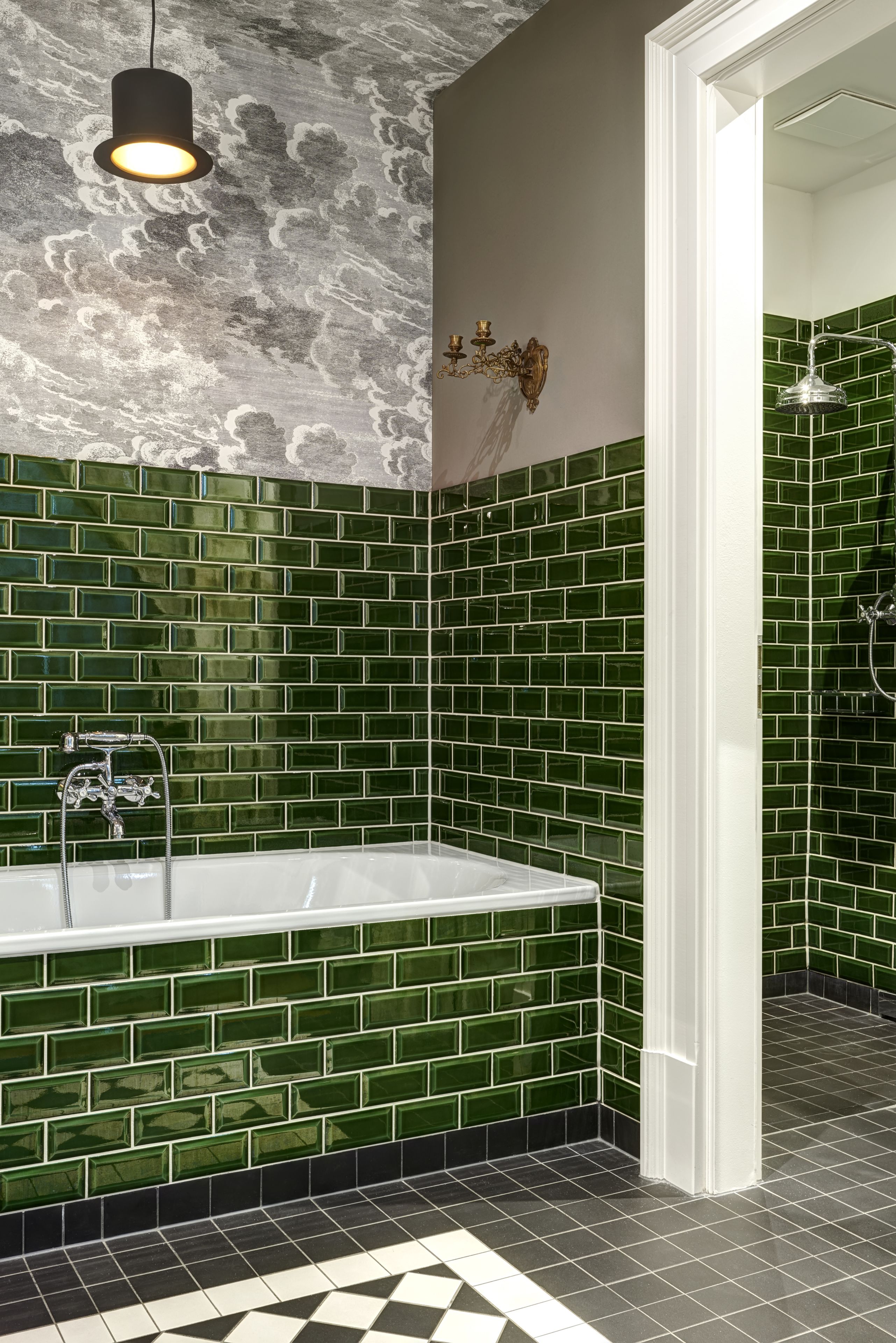 A bathroom with a large bathtub, green mosaic tiles, a white sink, and a shower area.