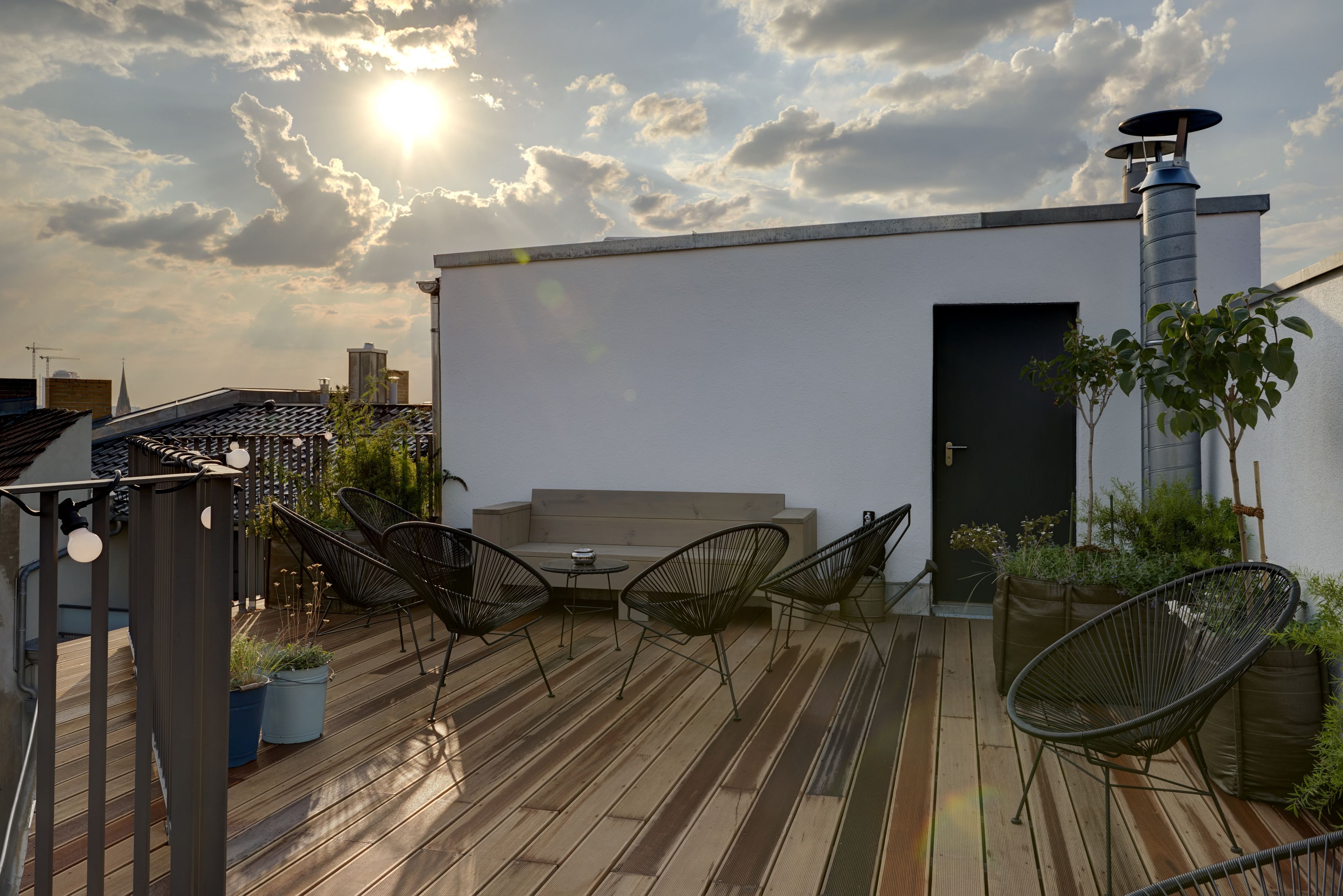 Una terraza en la azotea con piso de madera, mobiliario exterior y una chimenea.