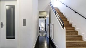 Un pasillo que lleva a una escalera de madera con piso negro.