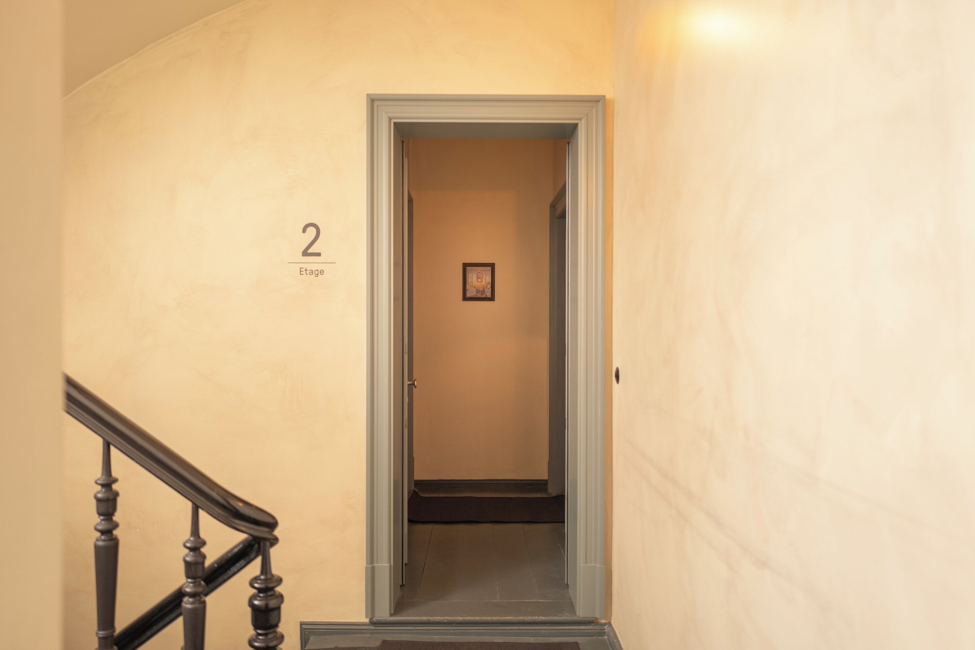 A narrow hallway with a wooden staircase on the left and a door labeled "2" on the right.