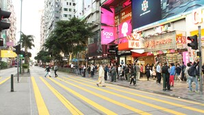 Une rue animée en milieu urbain, où des piétons traversent sur un passage piéton.