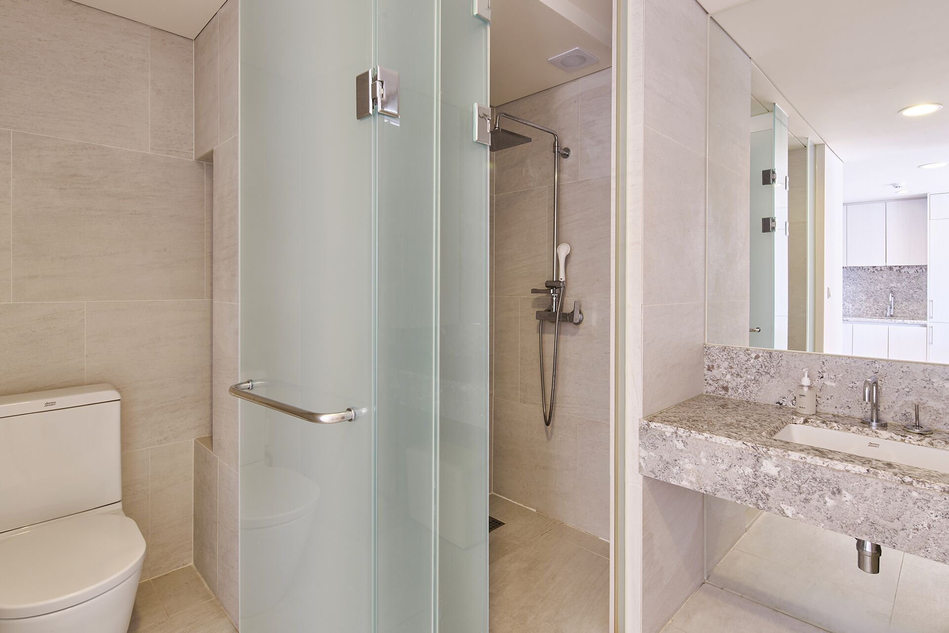 A modern bathroom with a glass shower enclosure, a toilet, and a marble sink with a mirror above it.