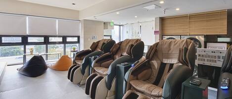 Une salle de massage équipée de plusieurs fauteuils de massage, d’un fauteuil en forme de sac de haricots et d’un espace dédié au linge.