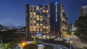 Un hôtel moderne, avec plusieurs étages, des fenêtres illuminées et une enseigne bien visible.