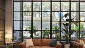 Un salon moderne avec un canapé en cuir, une table basse et de grandes fenêtres donnant sur un jardin.
