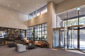 Un vestíbulo amplio con techos altos, ventanas grandes y puerta giratoria.