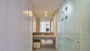 Un couloir moderne avec un comptoir en marbre, une cabine de douche en verre et un banc beige.