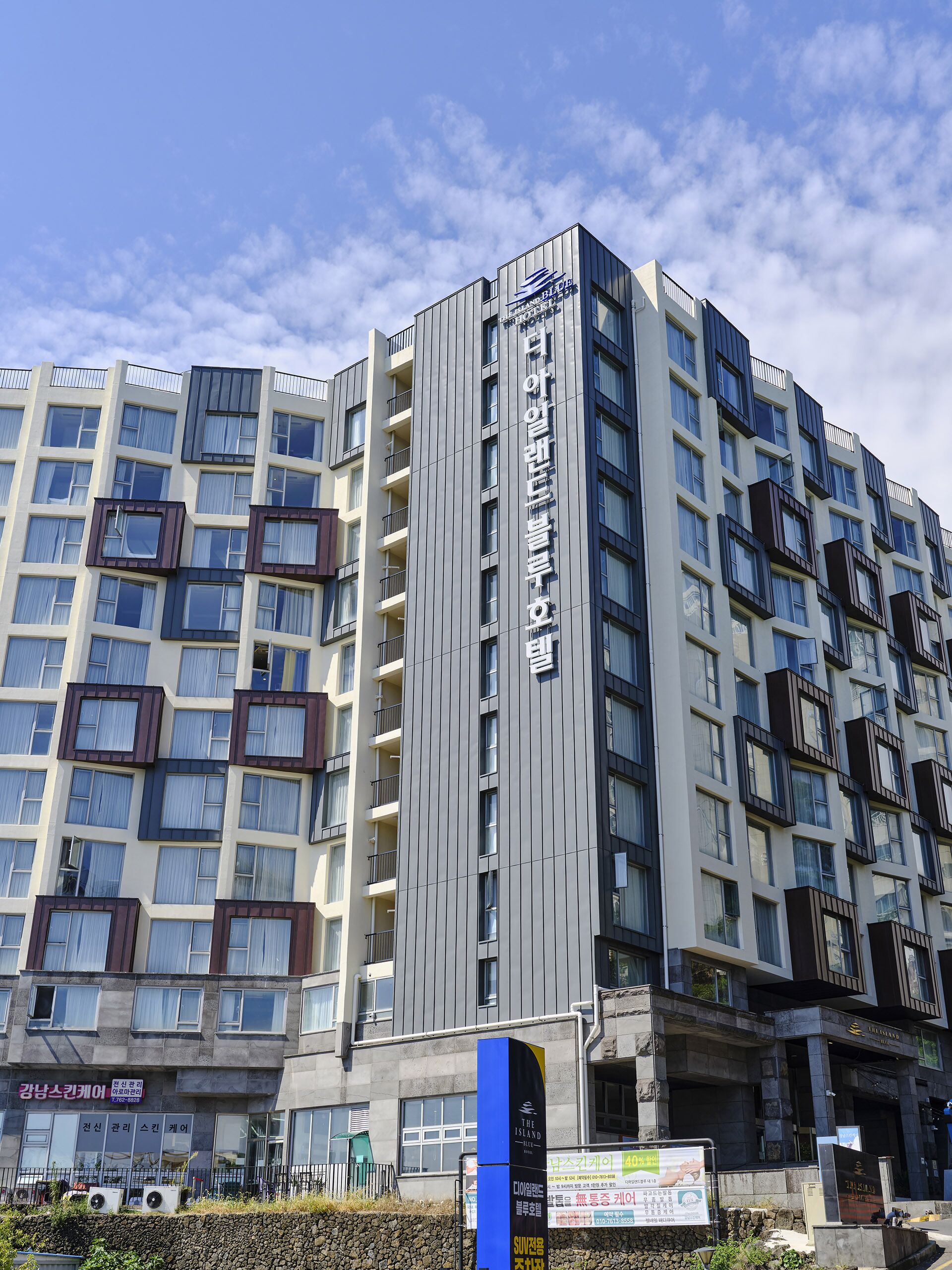 A multi-story hotel with a modern design, featuring balconies and a prominent sign.