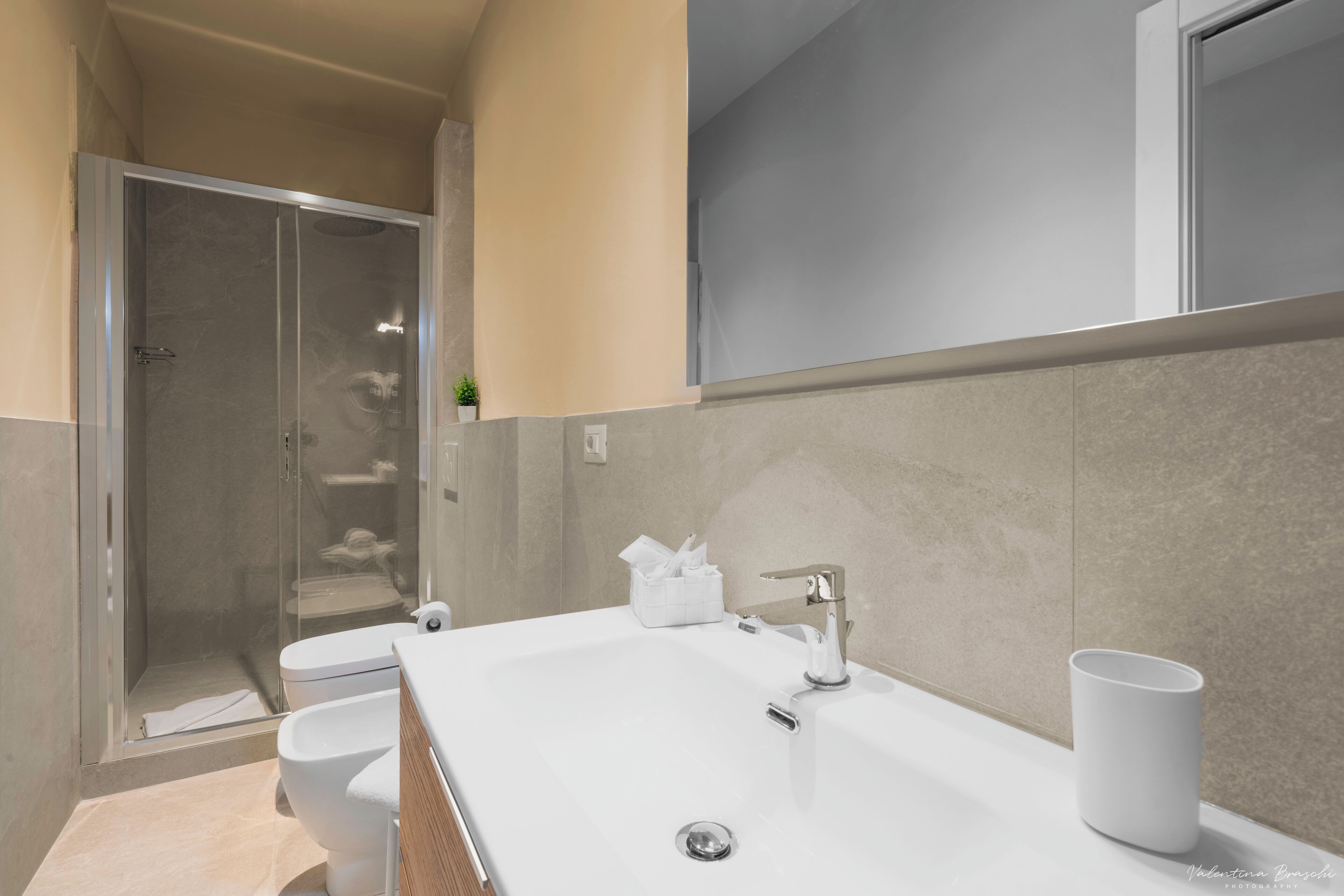 A modern bathroom with a glass-enclosed shower, a white sink, and a toilet.