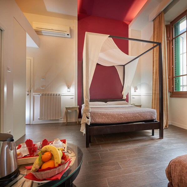 A bedroom with a four-poster bed, a bedside table with a fruit basket, and a radiator. - Le Stanze del Duomo (Florence)