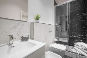 A modern bathroom with a white sink, a toilet, and a glass-enclosed shower area. - Le Stanze del Duomo (Florence)
