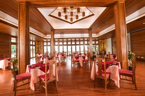 A spacious dining area with wooden paneling, large windows, and a central chandelier. - Bagan Thiripyitsaya Sanctuary Resort (Nyaung-U)