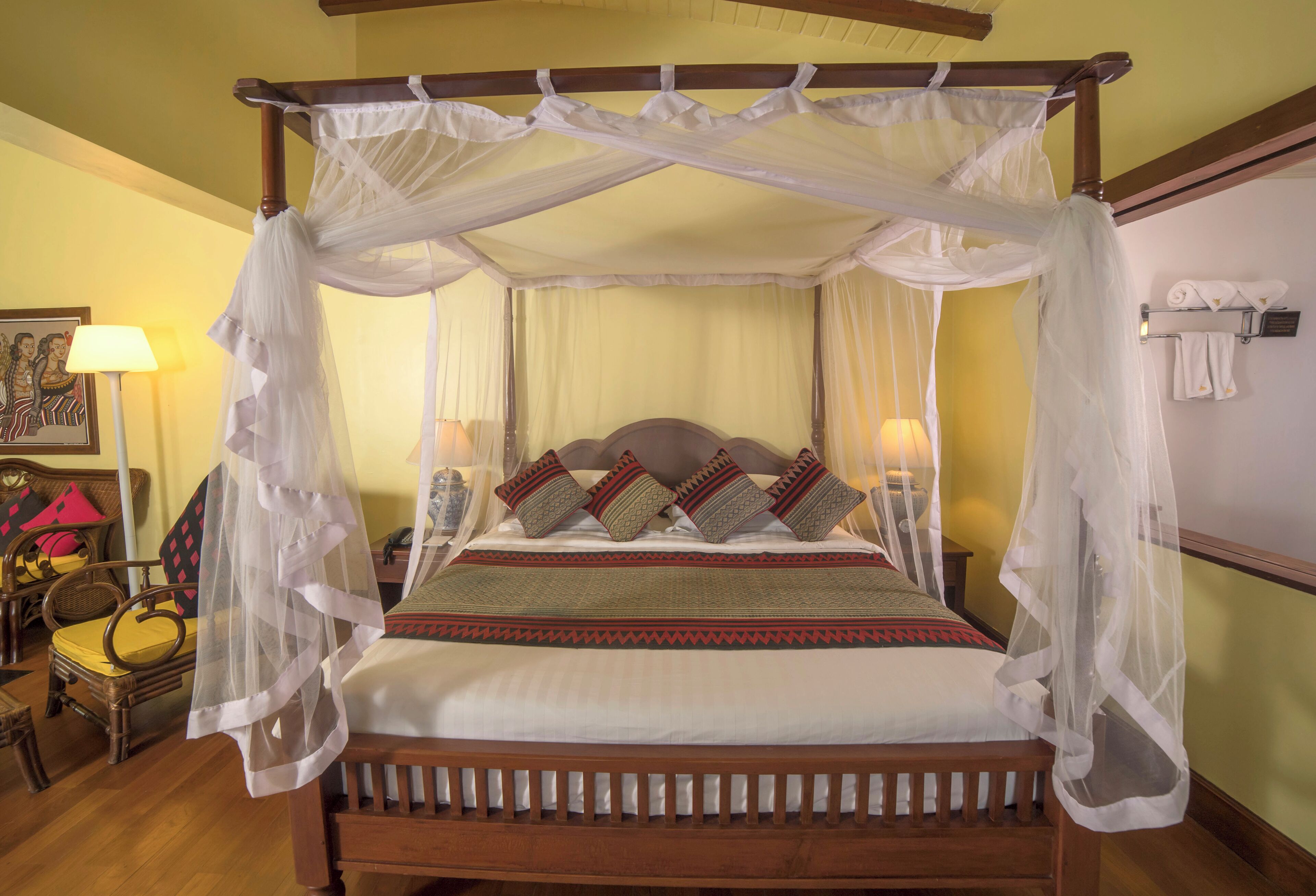 A four-poster bed with a canopy, a wooden headboard, and multiple pillows.