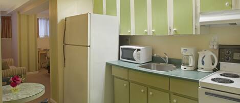 A compact kitchen with a refrigerator, microwave, coffee maker, and stove.