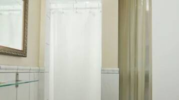 A bathroom with a pedestal sink, a mirror with a decorative frame, a shower with a curtain, and a radiator.