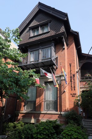A two-story brick building with a balcony, a flag, and a sign that reads "VICTORIA'S". - Victoria's Mansion Guest House (Toronto)