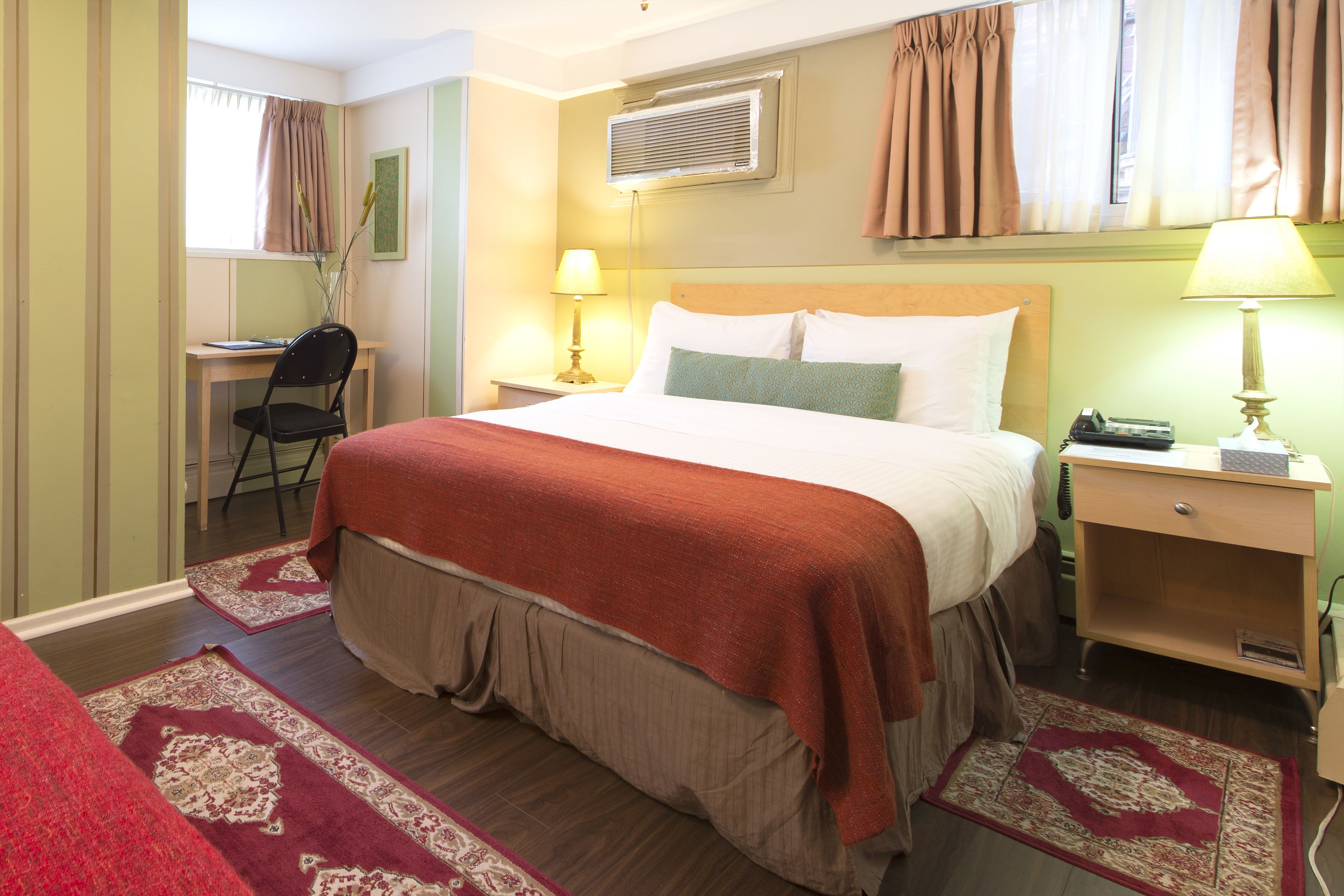 Een hotelkamer met een bed, nachtkastjes, een bureau en een stoel.