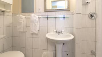 Un baño con inodoro, lavamanos y un perchero con toallas.