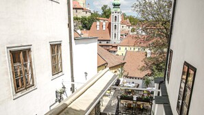 A rooftop terrace with tables and chairs, overlooking a historic town with distinctive architecture and a prominent tower. - Hotel Konvice (Cesky Krumlov)