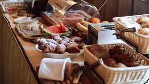 A buffet setup with various food items, a toaster, and a glass display case. - Hotel Konvice (Cesky Krumlov)