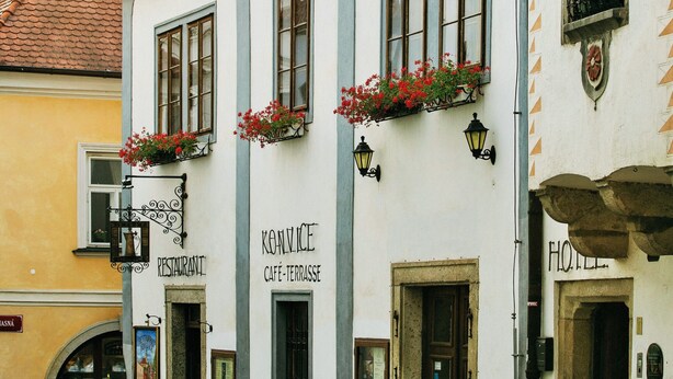 A building with a café terrace, restaurant, and hotel signs. - Hotel Konvice (Cesky Krumlov)