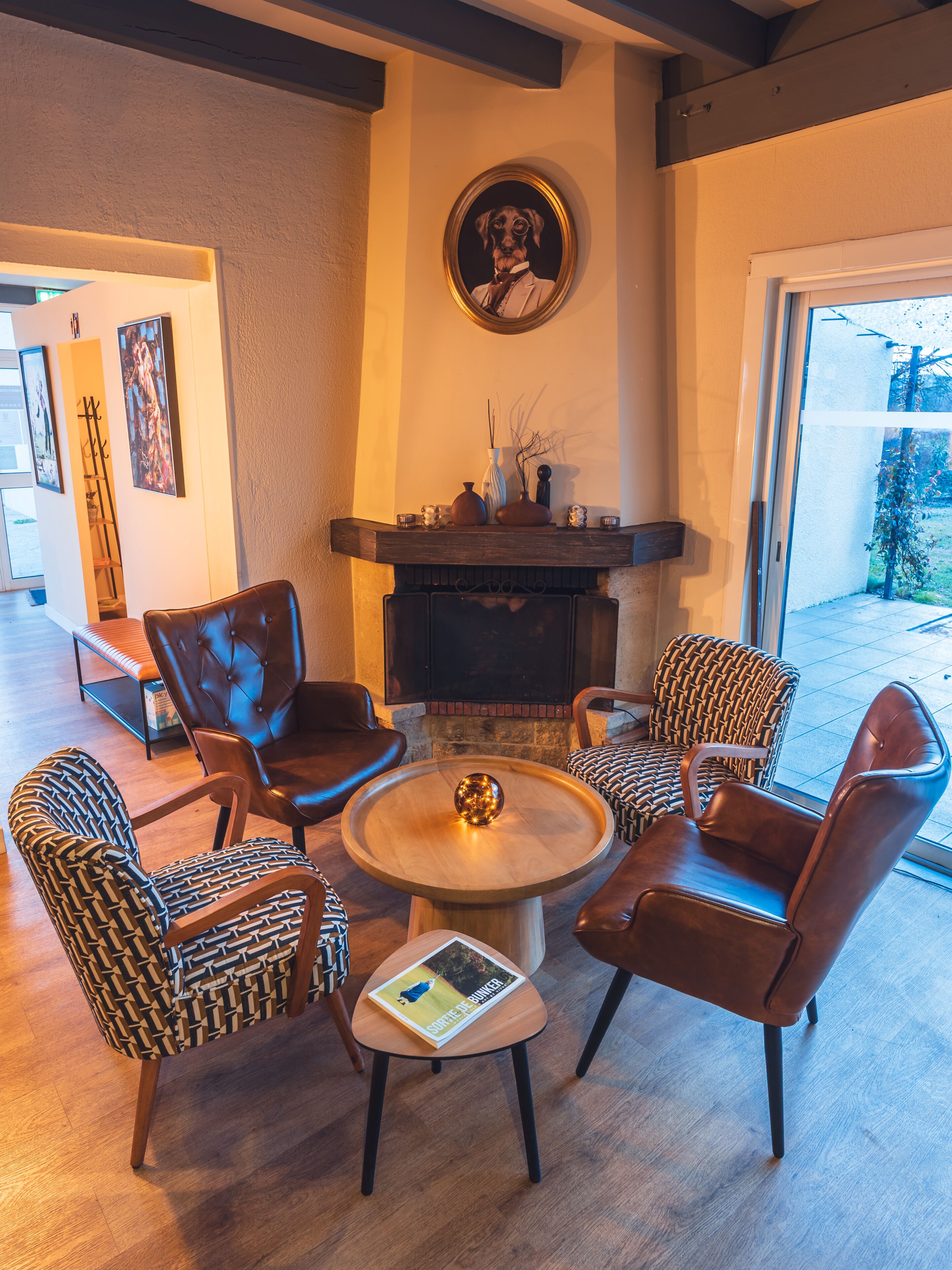 Una sala de estar acogedora con chimenea, sillones de cuero, una mesita de centro y un cuadro enmarcado en la pared.