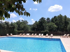 Una piscina al aire libre de temporada, sombrillas, tumbonas