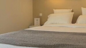 A bed with white linens and a grey blanket. - Golf Resort de Digne by Adonis (Digne-les-Bains)