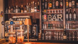 A bar area with a coffee machine, various liquor bottles, and a 'BAR' sign. - Golf Resort de Digne by Adonis (Digne-les-Bains)
