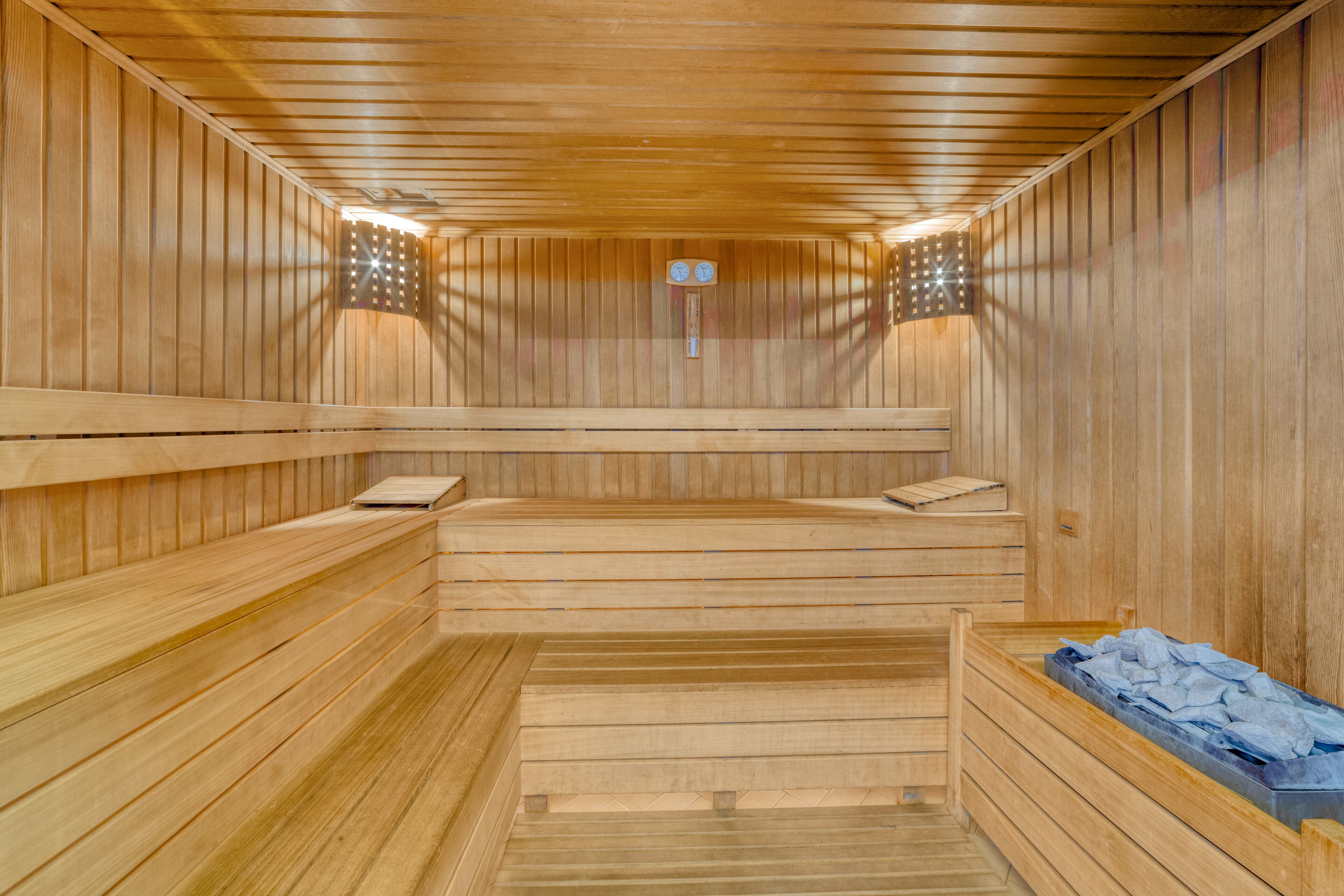 A sauna with wooden benches and a bench with towels.