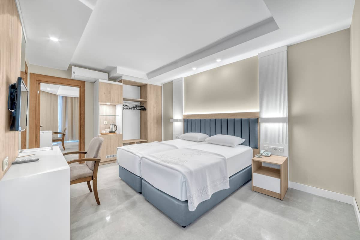 A modern bedroom with a double bed, bedside tables, a desk, and a chair.
