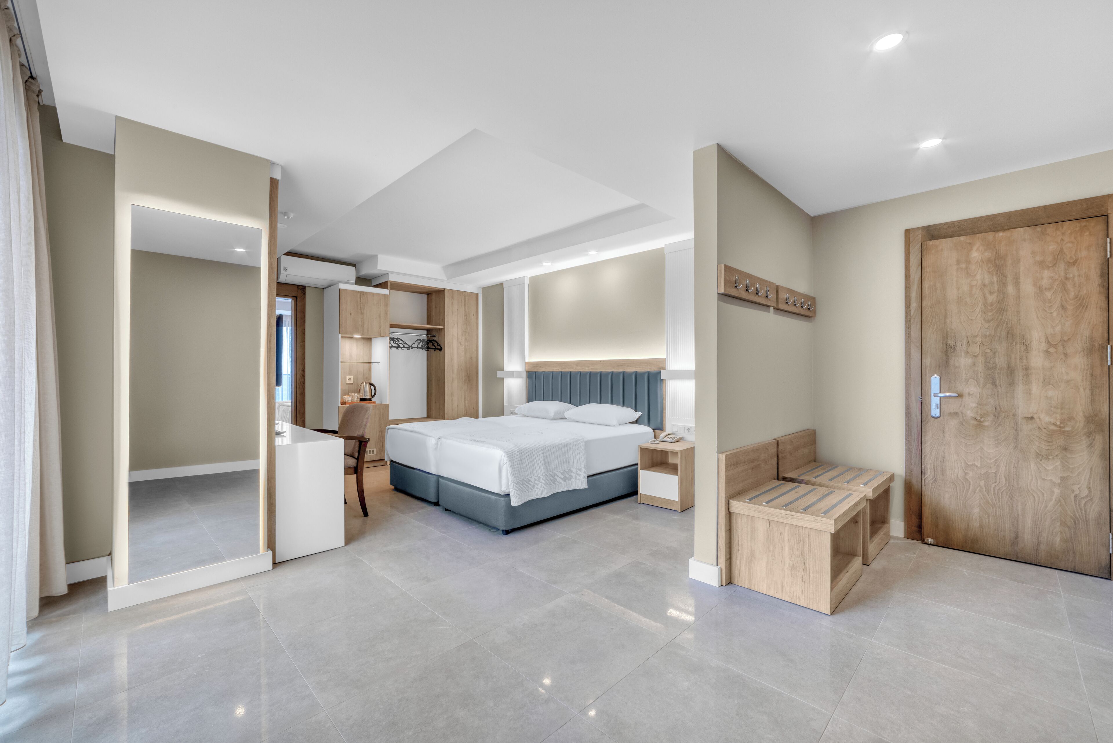 Ein modernes Schlafzimmer mit einem großen Bett, Nachttischen, einer Holzbank und einem Kleiderschrank.