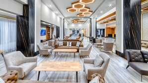Un vestíbulo amplio con una zona de estar central, iluminación moderna y vistas al área de comedor.