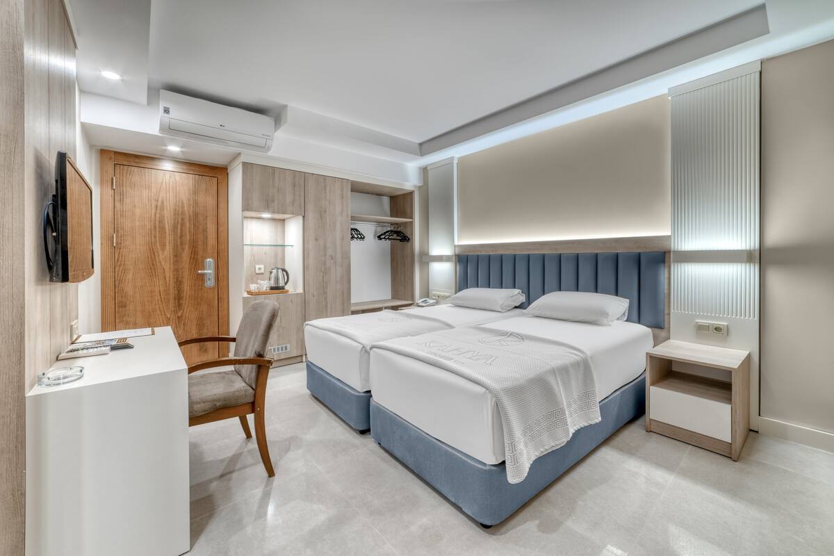 A modern bedroom with a double bed, bedside tables, a desk, and a chair.