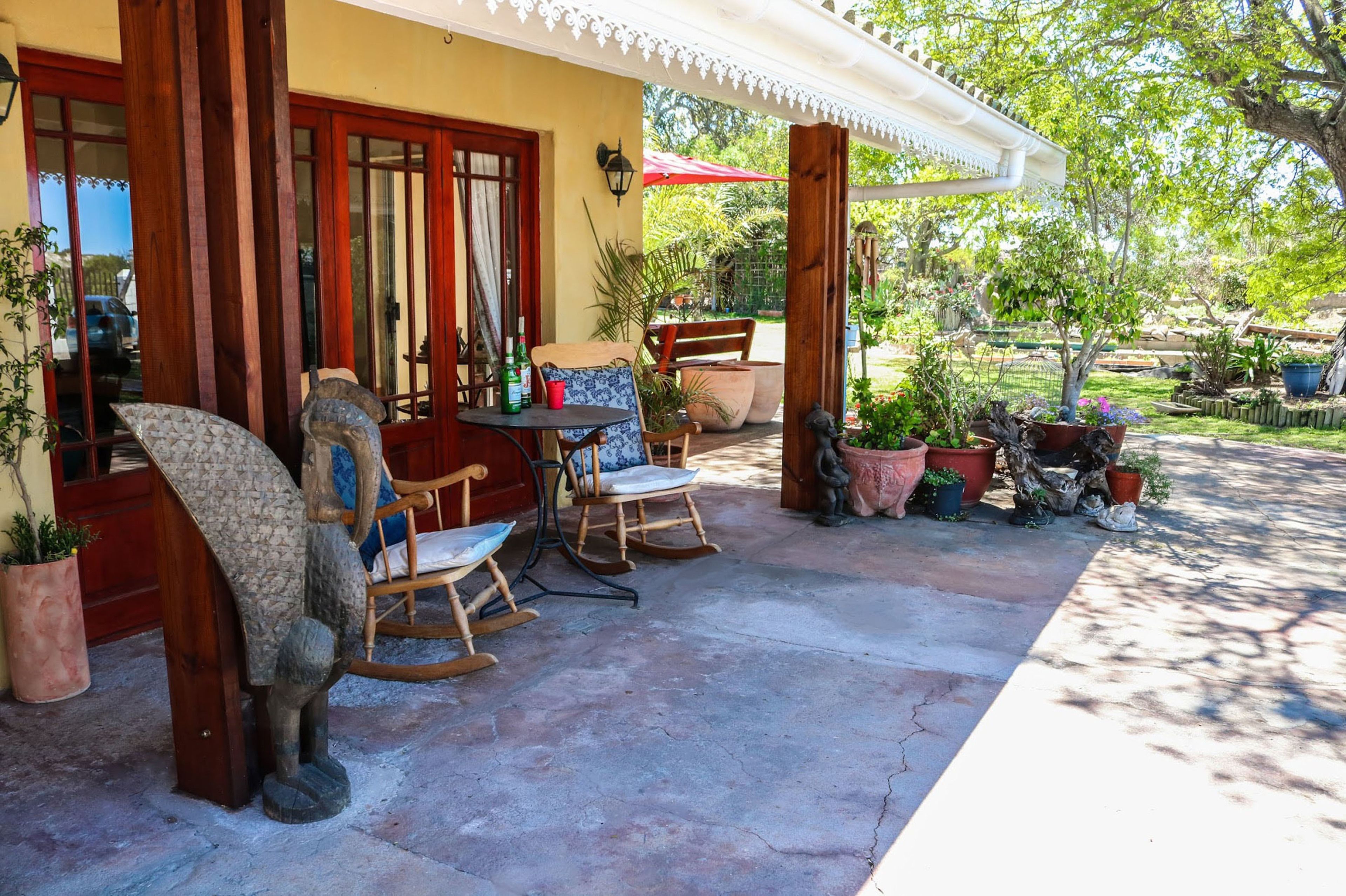 A patio with a table, chairs, and potted plants.