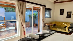 Une chambre d’hôtel avec un lit, un canapé jaune, une petite table et une fenêtre avec des rideaux.