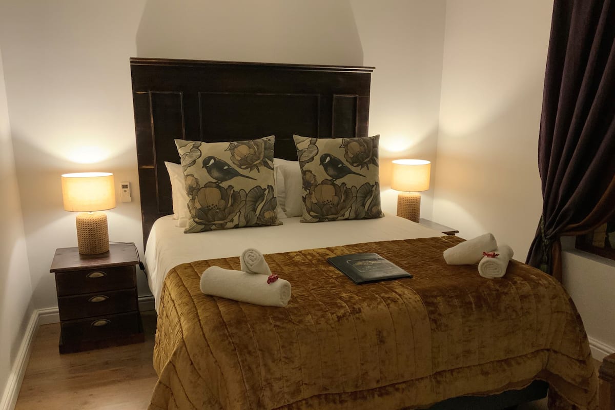 A hotel room with a large bed, two nightstands, a bedside lamp, and a pillow with a bird design.
