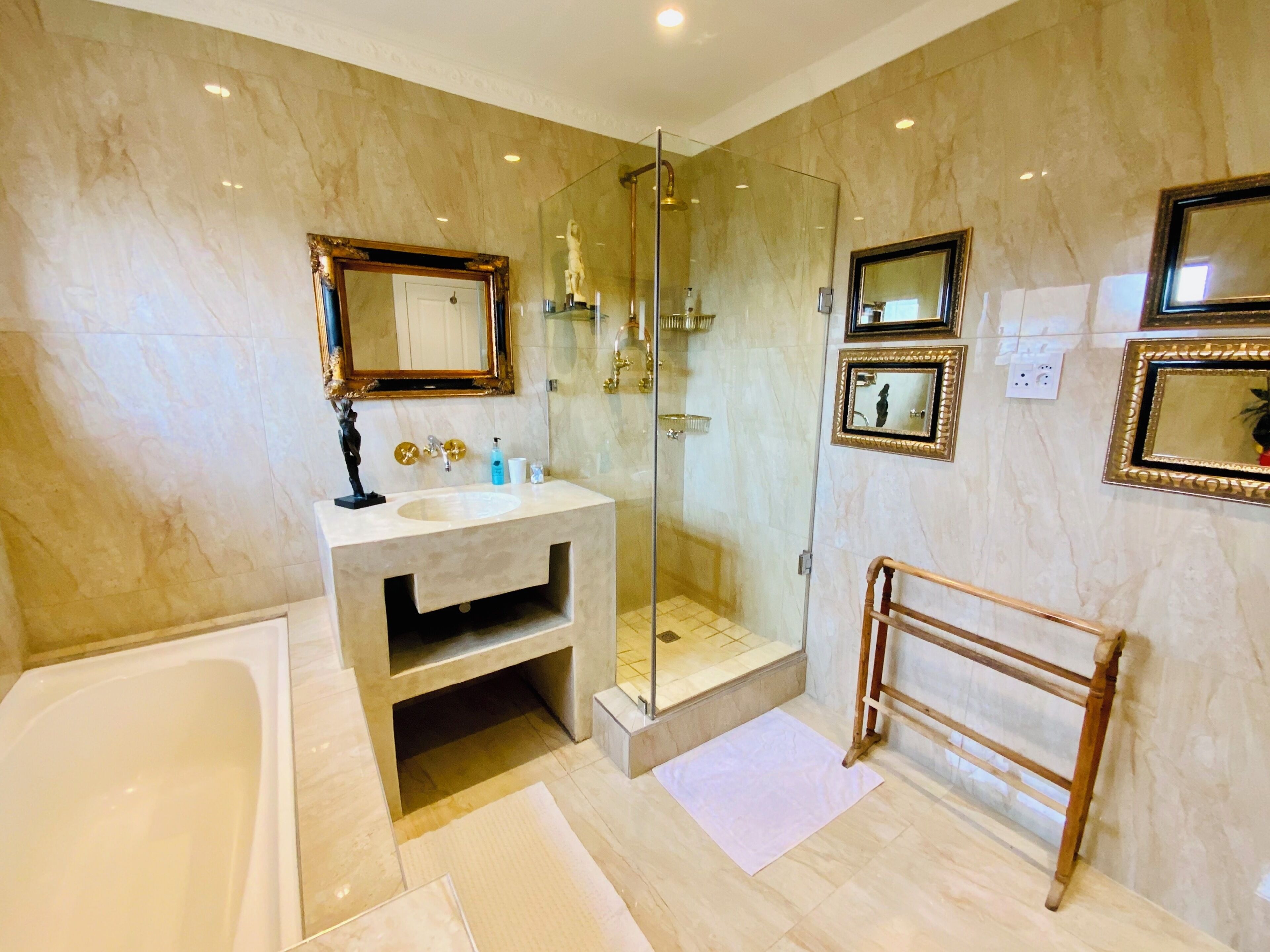 Un bagno con una vasca, una cabina doccia in vetro, un lavabo con specchio e un portasciugamani in legno.