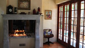 A fireplace with a stone surround, a clock, and a painting on the wall. - Goblin's Mead (Cape Town)