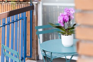 A round table with a white pot of purple flowers, a blue chair, and a blue railing in the background. - Roof Garden Zaccardi (Rome)